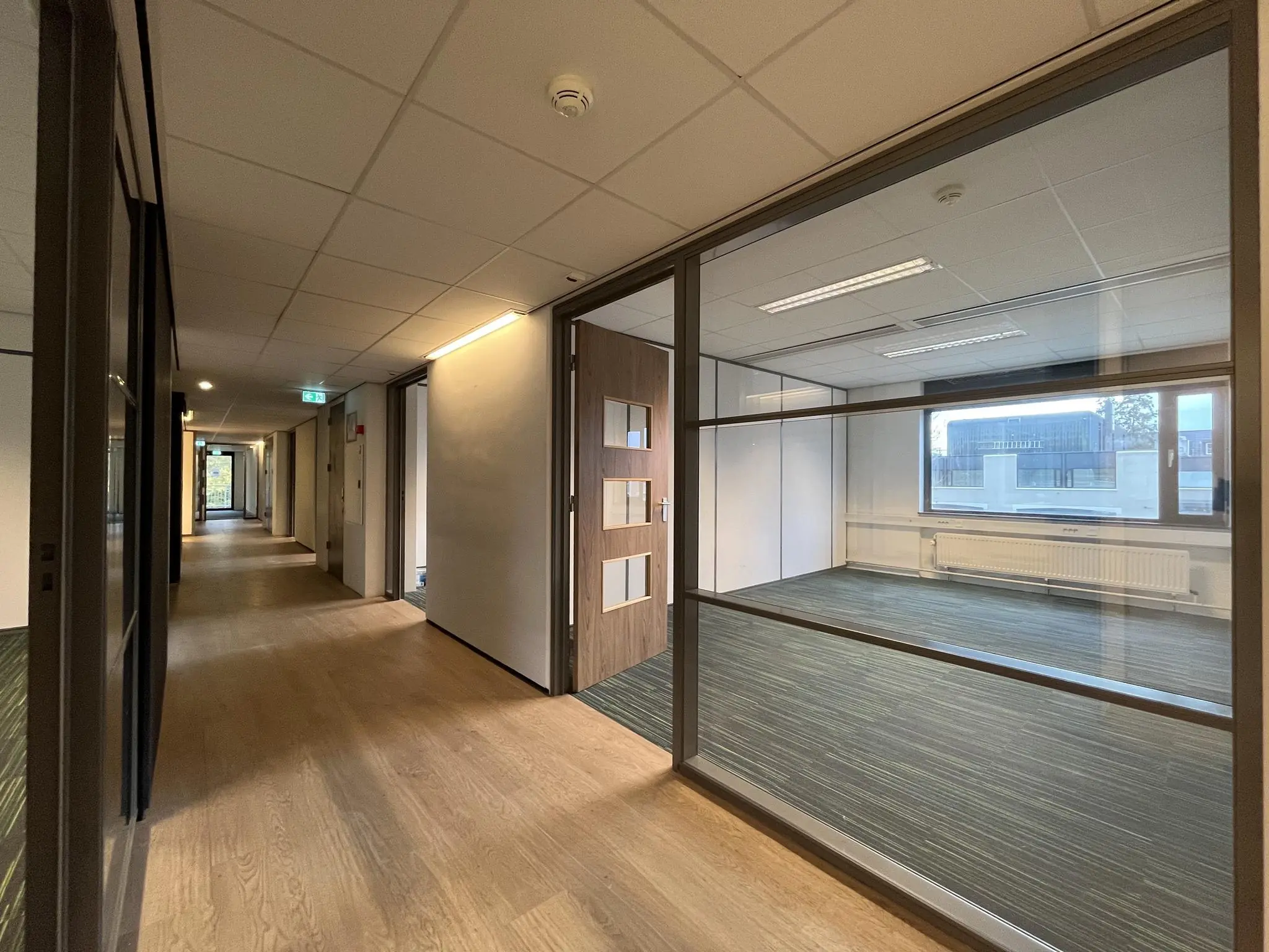 Moderne kantoorhal met houten vloer en glazen wanden aan de Burgemeester Verderlaan.